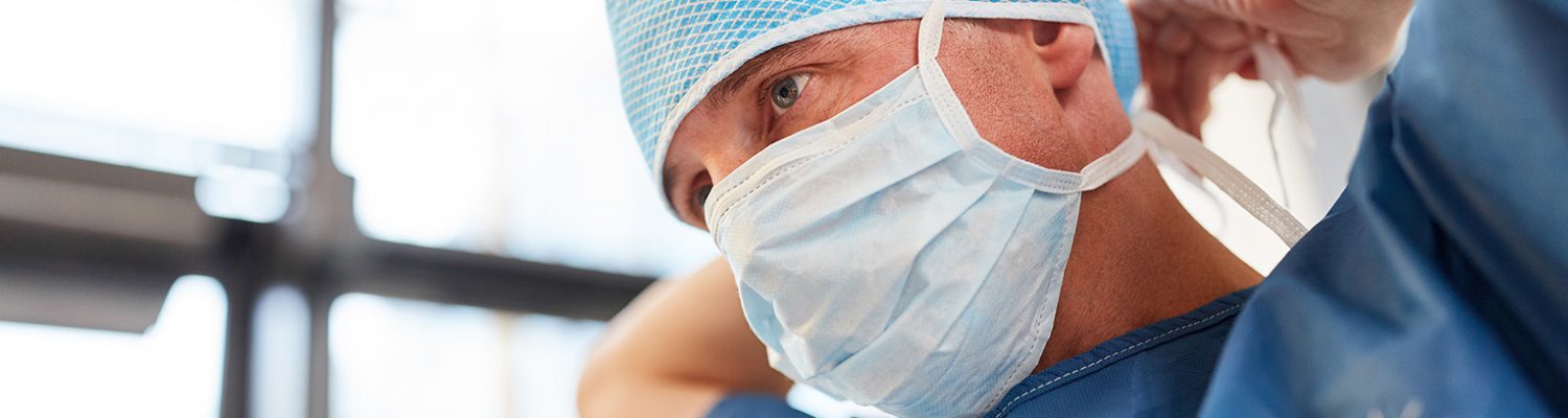 Surgeon in blue surgical gown binds the mouthguard for an emergency